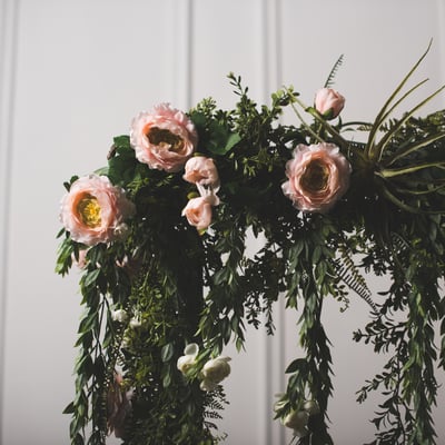 Large, faux pink bloom in greenery arch
